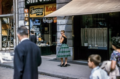 一个女人站在路边的商店旁，左顾右盼
